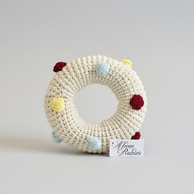 Crocheted doughut toy rattle with colourful polka dots on a studio background