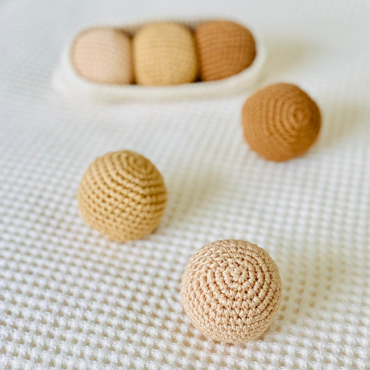 A set of handmade beige and brown textured balls, made from cotton thread and designed to fit in a crochet pod