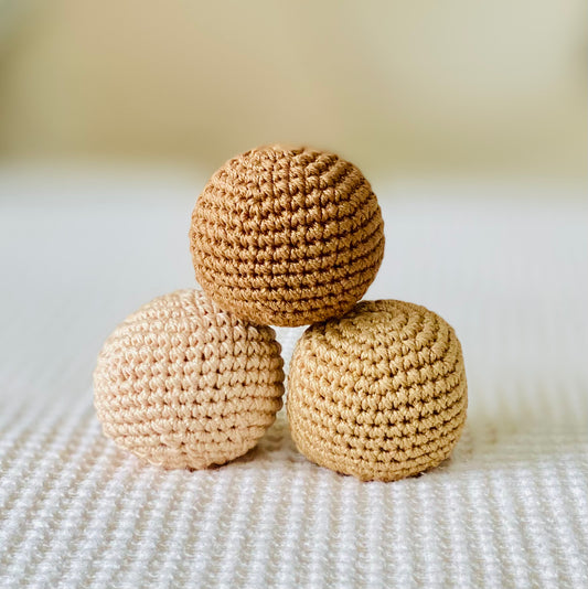 A set of handmade beige and brown textured balls, made from cotton thread and stacked on top of each other