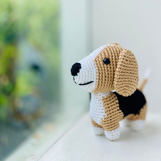 A crocheted beagle toy with floppy ears looking out the window.